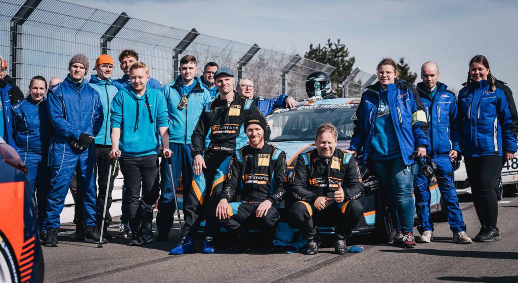 Mertens Motorsport, Teamfoto Anfang der Saison 2023, 16 Personen stehen oder hocken vor und neben dem i30n Hatchback