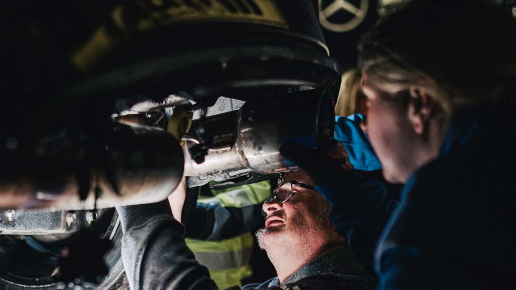 DIe Mechaniker von Mertens Motorsport inspizieren die Auswirkungen des Brandschadens in der Box